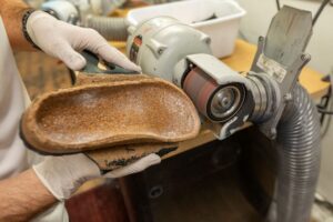 A custom orthotic being sanded to a specific dimension.